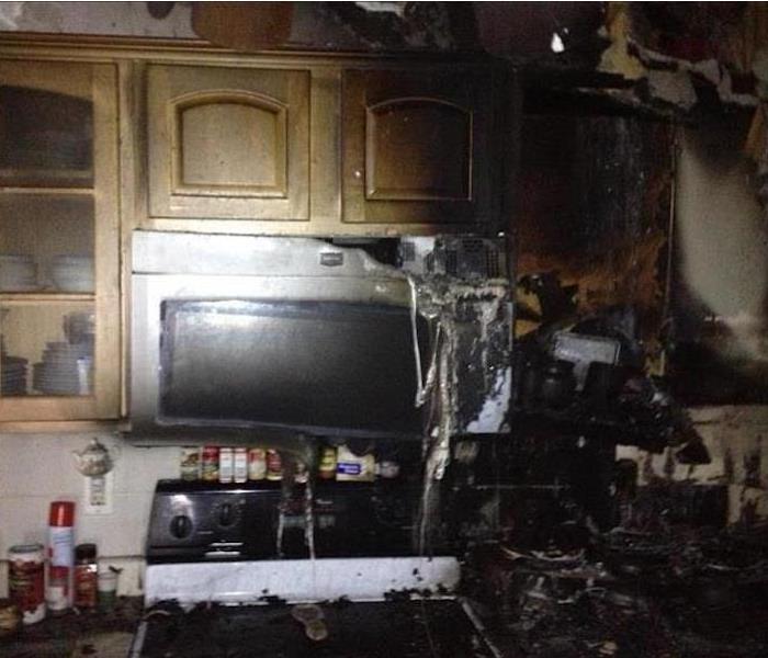 kitchen with cabinets and microwave burned and covered in soot
