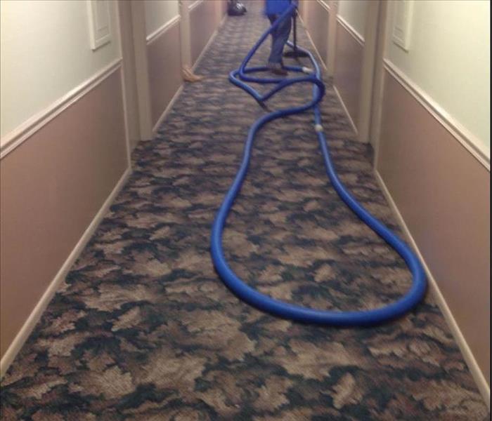 hotel hallway with employee extracting water with a vacuum