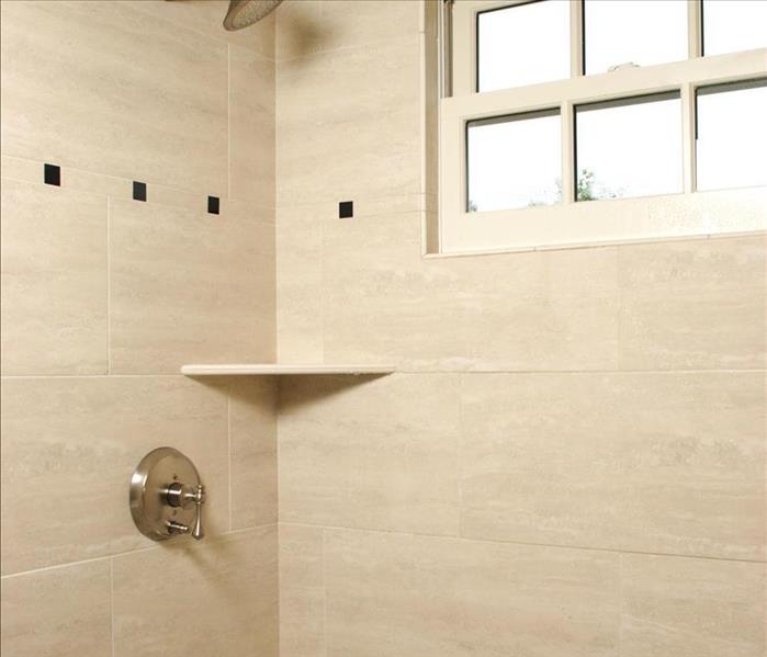tan tiled shower with a shelf