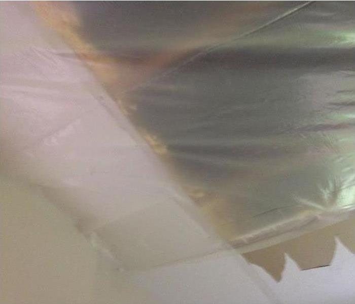 white ceiling with drywall removed and covered with plastic sheeting