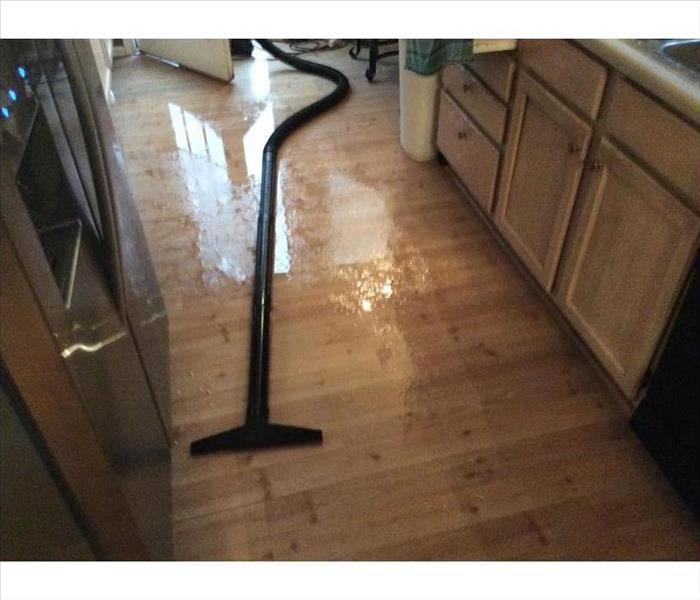 hardwood flooring in a kitchen covered with water and a vacuum