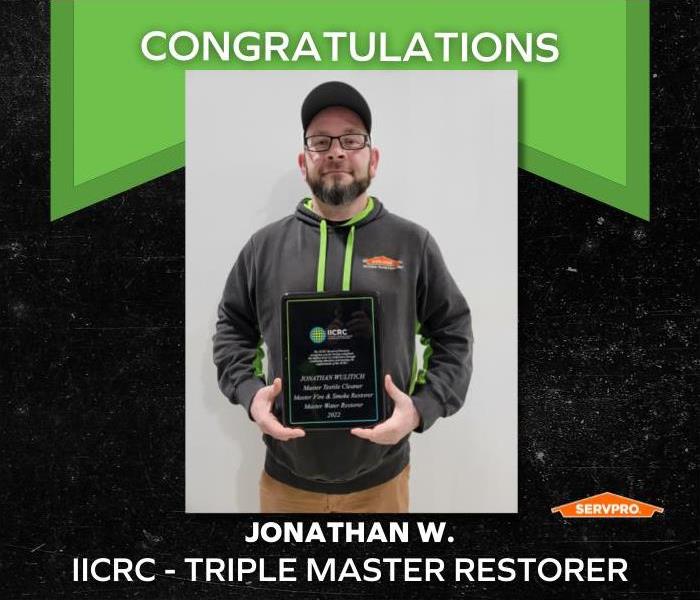 male employee holding an IICRC Triple Master Restorer plaque