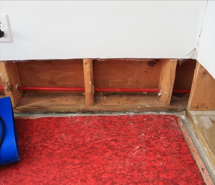 red carpet padding and exposed framing on the bottom two feet of the wall