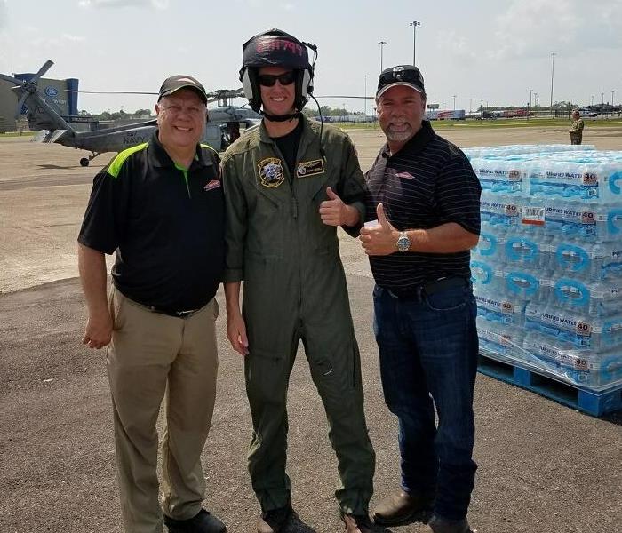 two SERVPRO employees standing with a pilot giving a thumbs up