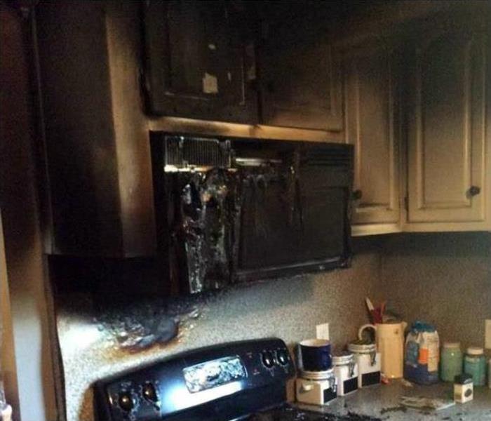 kitchen cabinets and microwave covered in soot damage