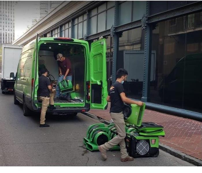 SERVPRO techs moving water damage equipment into storm damaged building