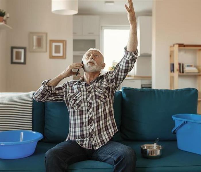 A man sitting on a couch with buckets on the phone. 