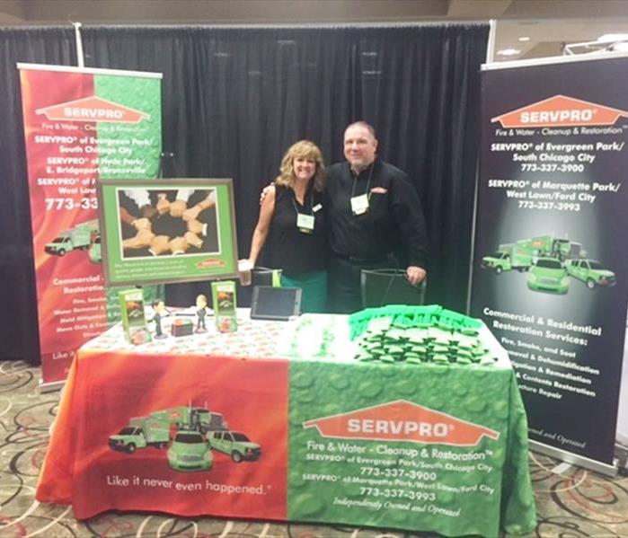 two employees standing behind a table with SERVPRO promotional items