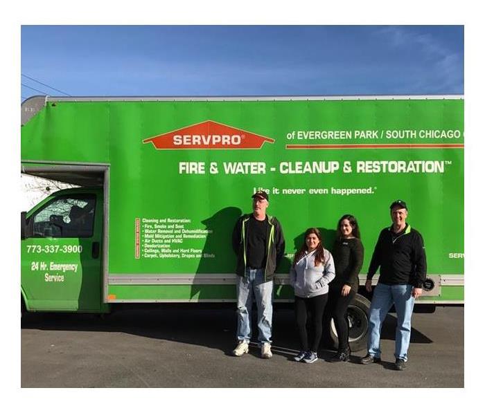 four SERVPRO employees standing in front of a green SERVPRO box truck