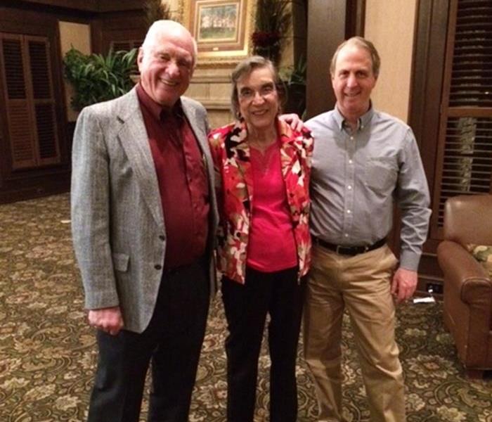 SERVPRO employee standing with the two founders of SERVPRO in a hotel lobby