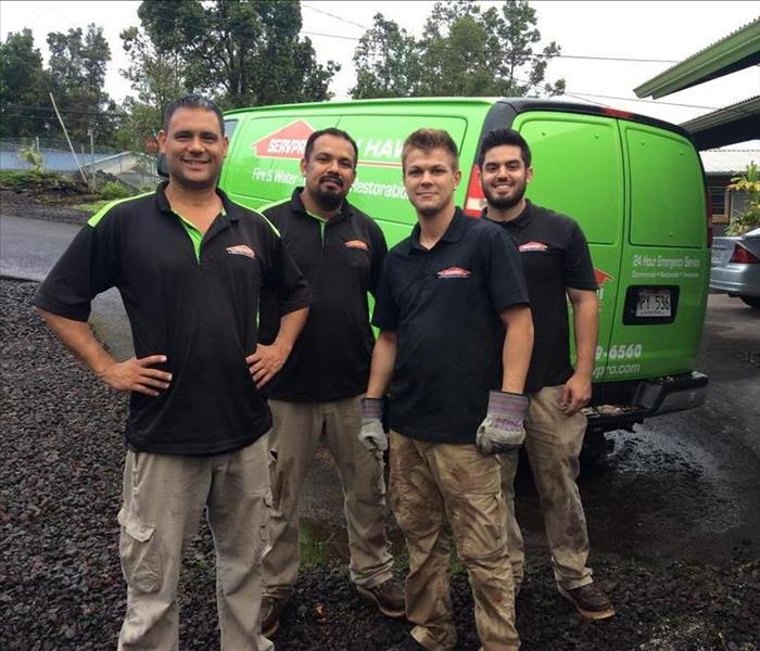four male employees standing in front of a green SERVPRO van