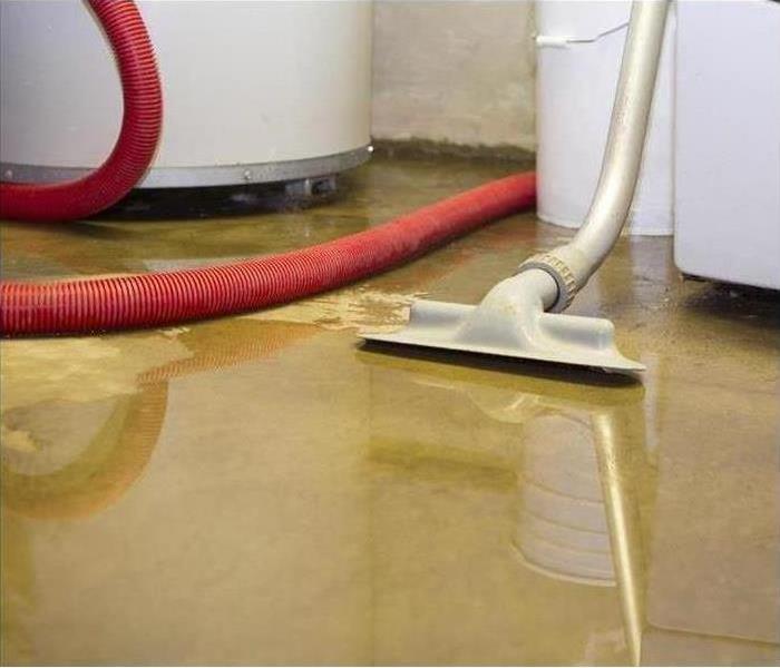 flooded floor by water heater with a vacuum head and read hose shown